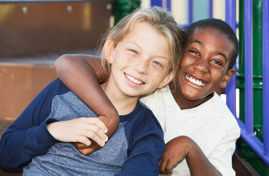 Happy African and Caucasian male child friends on playground set