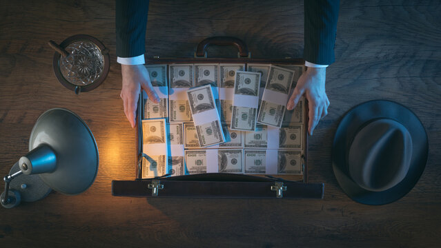 Vintage rich businessman's desk holding a briefcase filled with dollar packs, top view