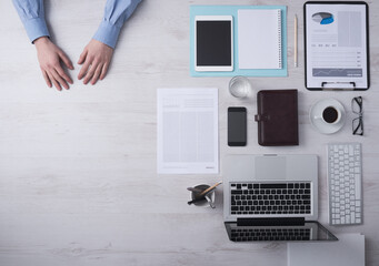 Businessman working at office desk hands detail with copyspace and various objects on the right, top view