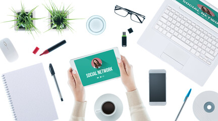 Social network user interface on laptop and tablet and woman logging in, desktop top view