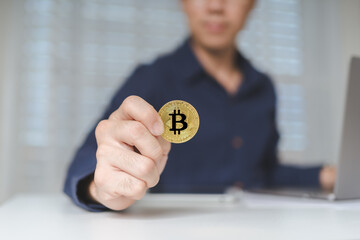 Bitcoin Cryptocurrency investment. Trader or investor hand holds Bitcoin Cryptocurrency logo gold coins. Business man shows logo Bitcoin Cryptocurrency on hands, using laptop for trading and investing - 622126326