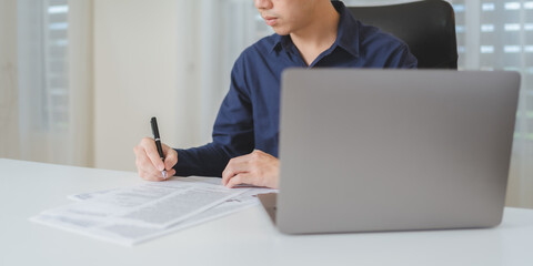 Businessman hand holds pen, writing on business paperwork for accept agreement contract on business investment project. Young adult business man signing on financial document deal. Copy space. Banner. - 622126362