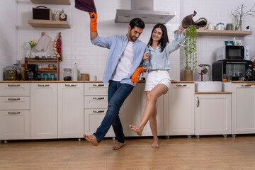 Young happy couple having fun while doing cleaning kitchen together