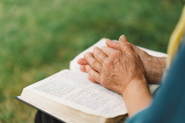Bible, reading book or old woman praying for hope, help or support in Christianity religion or holy faith. Prayer or senior person studying or worshipping God in spiritual literature at outdoors