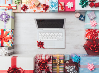 Laptop with ribbon and plenty of gifts on a wooden table, top view, celebrations and Christmas...