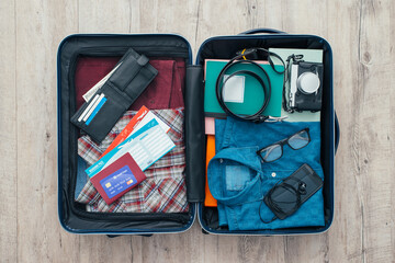 Open traveler's bag with clothing, accessories, credit card, tickets and passport, travel and...