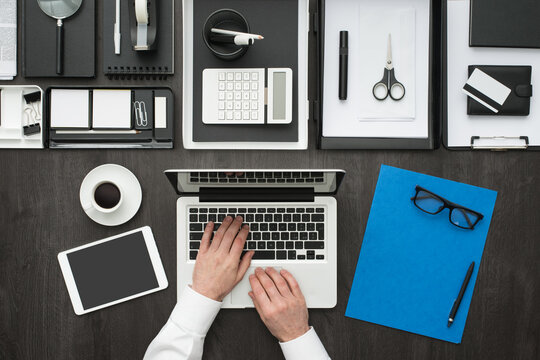 Corporate businessman working at office desk, he is networking with a laptop, flat lay