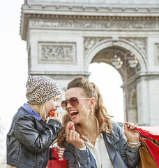 Stylish autumn in Paris. happy young mother and daughter with shopping bags in Paris, France eating...