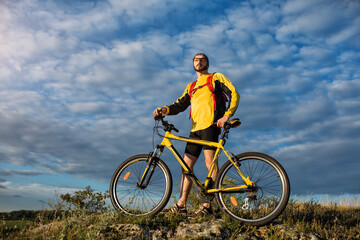 Fototapeta na wymiar Mountain Bike cyclist riding single track above sunset valley against blue sky
