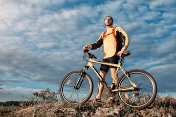 Fototapeta na wymiar Mountain Bike cyclist riding single track above sunset valley against blue sky