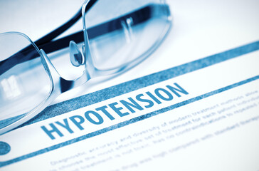 Hypotension - Low Blood Pressure - Medical Concept with Blurred Text and Pair of Spectacles on Blue...