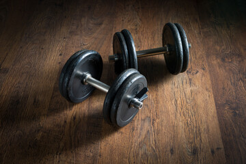 Obraz na płótnie Canvas Black barbell weights on dark hardwood floor, weightlifting training concept.