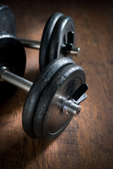 Obraz na płótnie Canvas Black barbell weights on dark hardwood floor, weightlifting training concept.