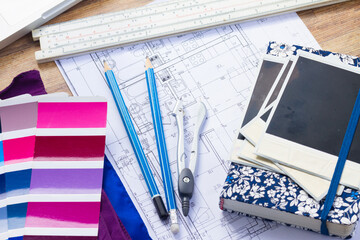 Interior designer's working desktop with architectural plan of the house, notebook, color palette...
