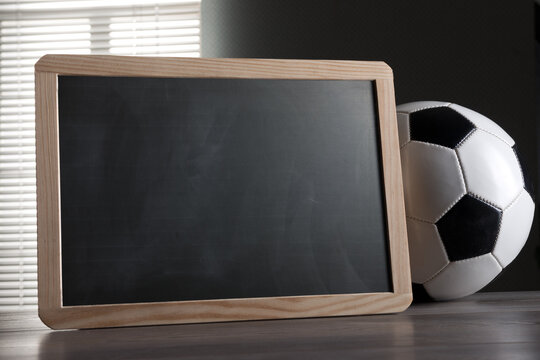 Small framed blackboard and soccer ball on a table.