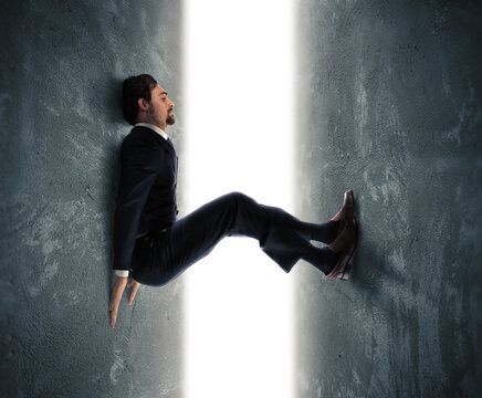 Businessman man trapped between two walls strives to push
