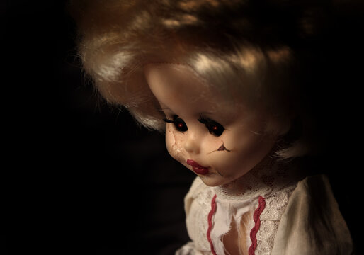Vintage evil spooky doll with cracked surface on the face and glowing eyes