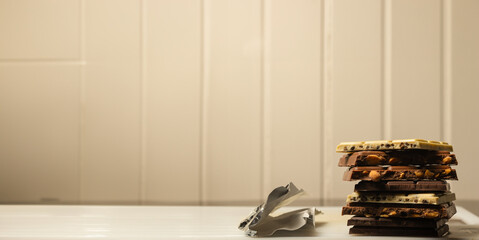 Chocolate chunk tower with peanuts, white chocolate and solid chocolate on white wooden background. Copyspace.