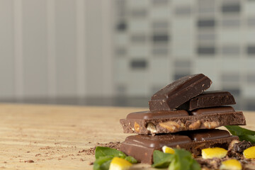 Focus on chocolate with 75% dark cocoa. It stands out for its flavor and intensity. Only for demanding. Composition on a wooden board and on milk chocolates and basil leaves.