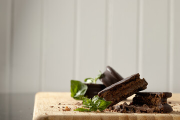 Chocolate alfajores on a wooden board. Basil leaves. Armed in still life. Argentinian Alfajor.