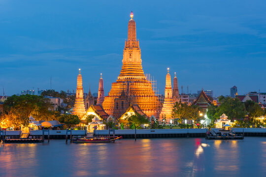 Large illuminated temple Wat Arun after sunset seen accross river Chao Phraya. Bangkok, Thailand