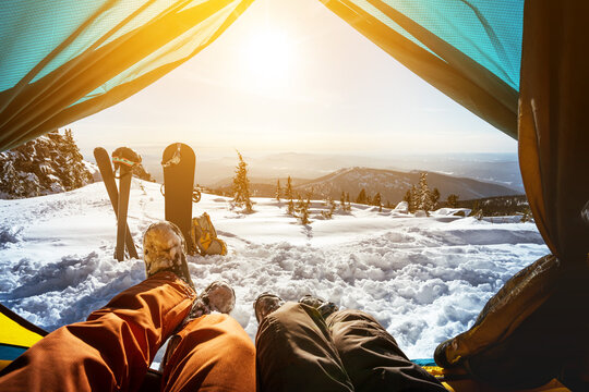 Couple of snowboarder and skier having rest in tent on the top of mountain