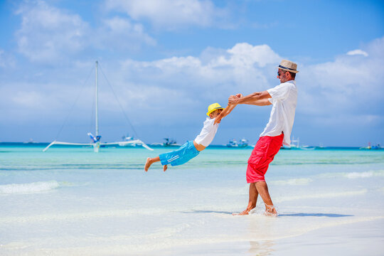 Father and son having fun on tropical white sand beach