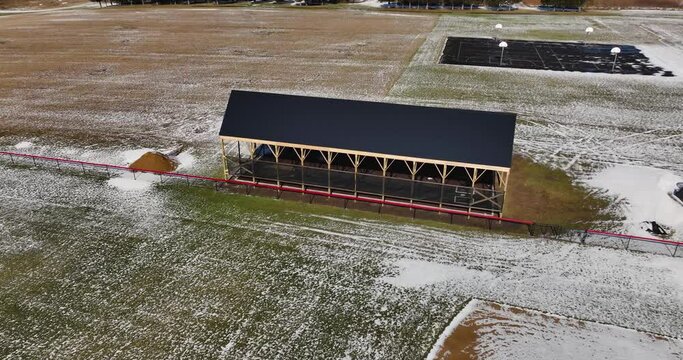 Aerial video of an outdoor batting cage with a covered wooden structure.