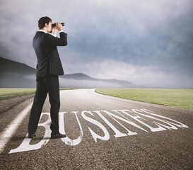 Businessman looks at the economic future with binoculars on the business road