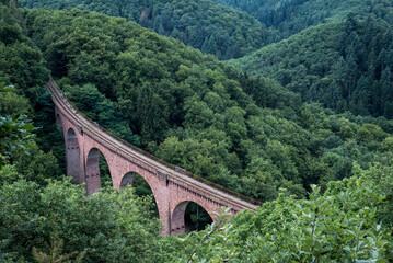 Fototapeta premium old arch Bridge railway viaduct between hills in the green Forest Germany trees