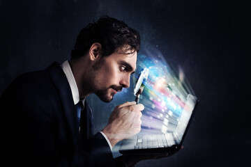 Businessman look with magnifying glass at the computer screen