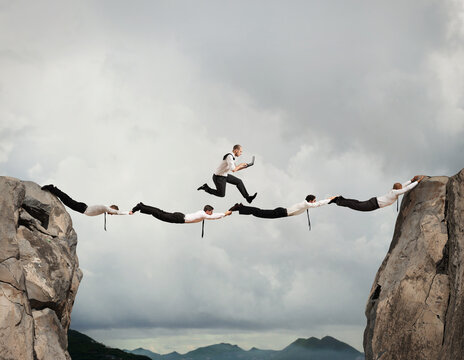 Businessmen working together to form a bridge between two mountains