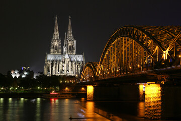 Cologne, Germany - October 16, 2013. Beautiful night view of the Cologne Cathedral and the bridge over the river. Golden lights reflected in the water. And no one around.