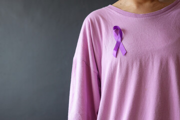 Close up of woman with purple domestic violence awareness ribbon on her chest over grey background....