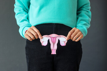 Woman holds female reproductive system paper shape in the hands. Health and cancer awareness...