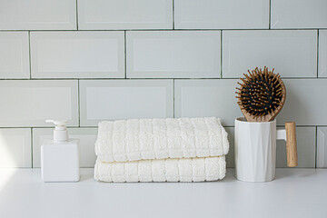 Wooden comb with white towel. tile wall background.