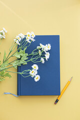 Blue book and flowers on yellow background