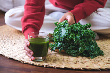 Closeup image of a young woman holding kale leaves and kale smoothies