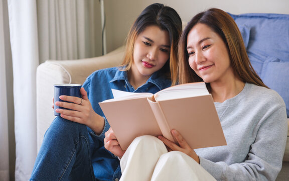 Portrait image of a young couple women enjoyed drinking coffee and reading books together at home