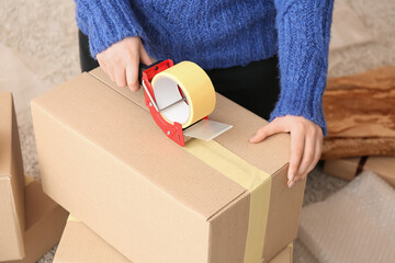 Woman packing cardboard box with adhesive tape dispenser