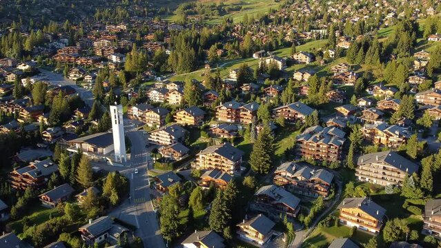 Verbier, Switzerland: Aerial drone footage of the famous Verbier mountain village with luxury chalets and the modern church in the Swiss alps in summer. 