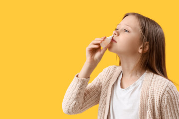Ill little girl with nasal drops on yellow background, closeup - obrazy, fototapety, plakaty