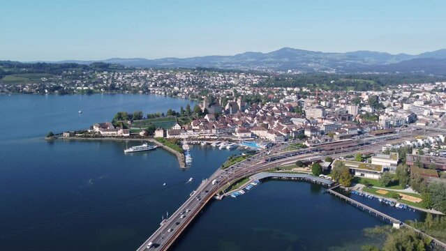 Rapperswil, Switzerland: Aerial drone footage of the bridge over Lake Zurich toward the Rapperswil-Jona city in canton Saint Gallen on the sunny summer day with a rotation motion. 