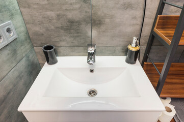 White ceramic sink in the kitchen with mixer tap and holder for liquid soap