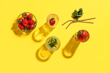 Glasses of fresh lemonade with strawberry and mint on yellow background