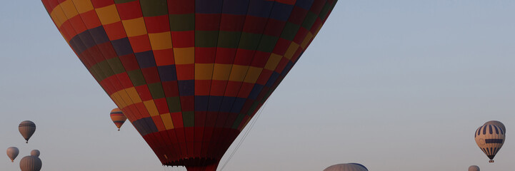 Multicolored big hot air balloon flying against blue sky