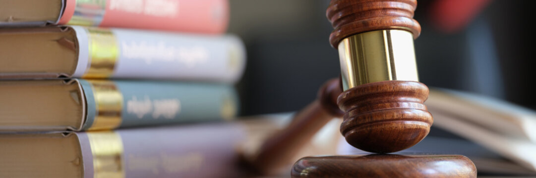 Wooden judge gavel and stack of legal book on table.