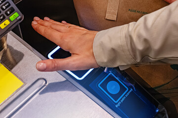 Close-up of woman scanning her palm to pay wireless at the cashier, futuristic payment technology