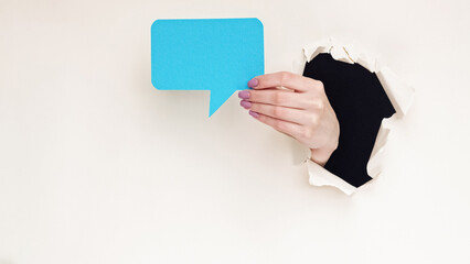 Online chat icon. Blank speech bubble. Female hand inside breakthrough paper black hole showing...