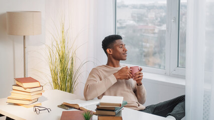 Coffee break. Morning ritual. Study relax. Dreamy peaceful young man drinking cup of hot tea...